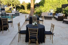 tables decorated with black tablecloths and flowers with 25 years balloons in background