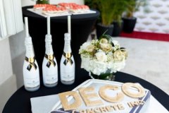 deco concrete cake on table by flowers and champagne bottles